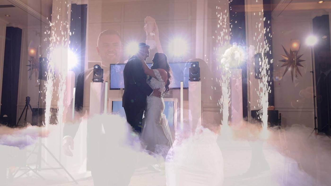 Couple's first dance surrounded by low dry-ice fog, with cold spark fountains firing on either side of them