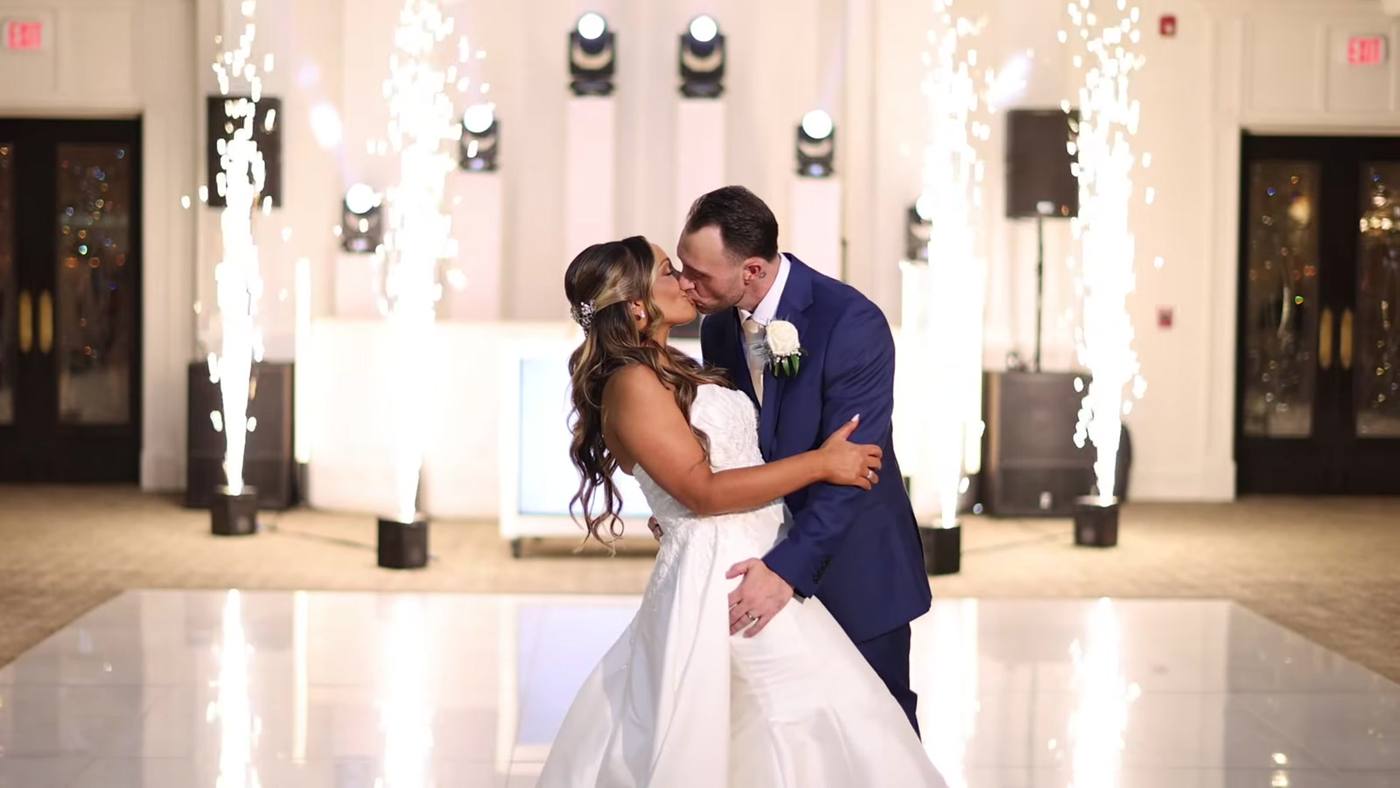 Newlyweds kissing alone on the dance floor as cold spark fountains fire behind them