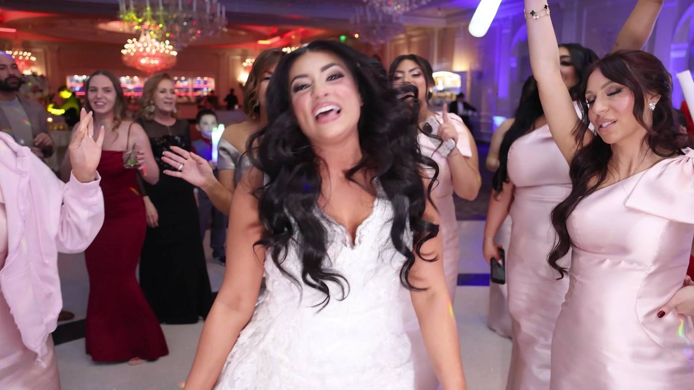 Bride singing and dancing surrounded by her bridesmaids in blush dresses